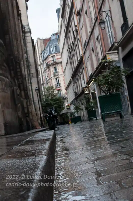 Je profite d'une légère accalmie pour m'accroupir et prendre la photo des cette rue et des pavés mouillés par la pluie en contre plongée.