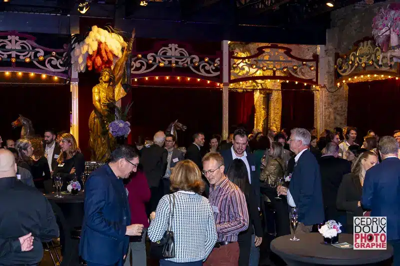 Invités dans la salle principale du Musée des Arts Forains lors des 15 ans d'ICOSA, ambiance festive avec lumières.