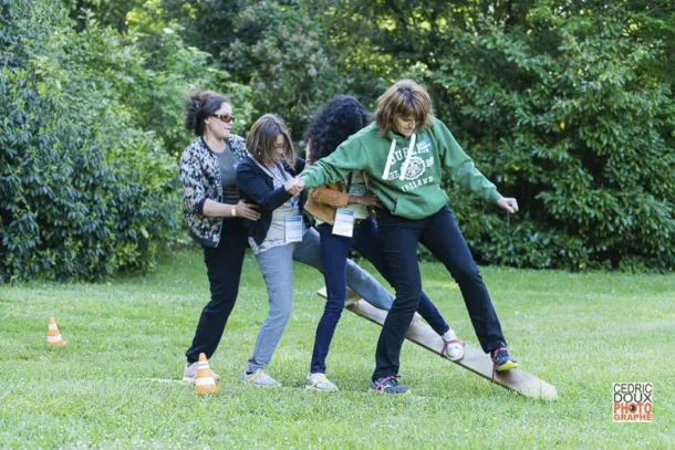 Image de l'entreprise, raconter votre histoire 3 Groupe de collaboratrices s’entraidant lors d’un atelier parcours sur planches en plein air pendant un séminaire d’entreprise