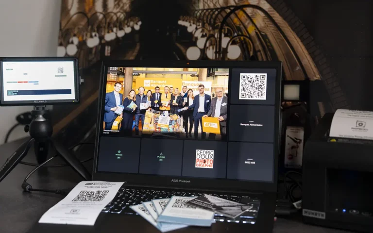 Configuration PhotoCall Live avec ordinateur affichant la galerie des Banques Alimentaires, QR codes et impressions associés